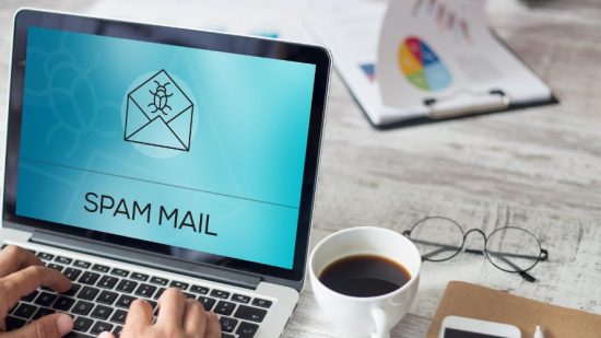 Spam-E-Mail wird als Schrift auf einem Laptop angezeigt, der auf Schreibtisch steht